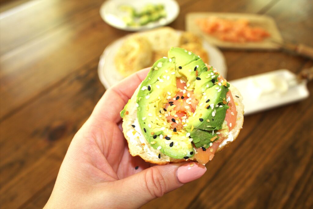 Image of a sourdough bagel topped with cream cheese, smoked salmon, and avocado.