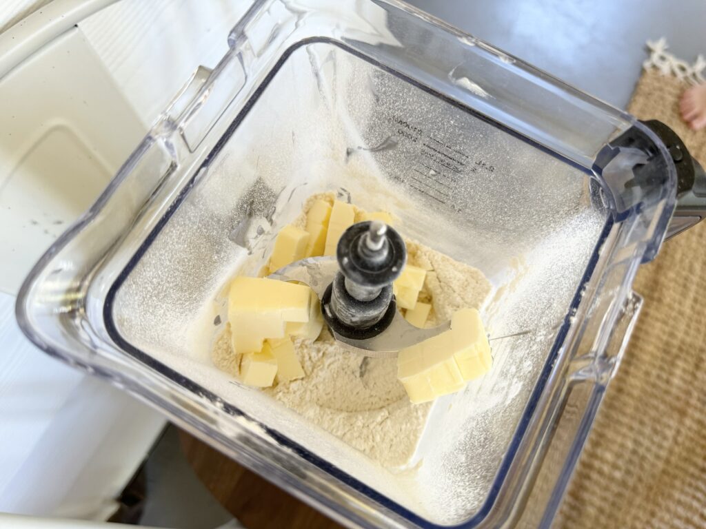 Food processor bowl containing flour sugar salt and butter