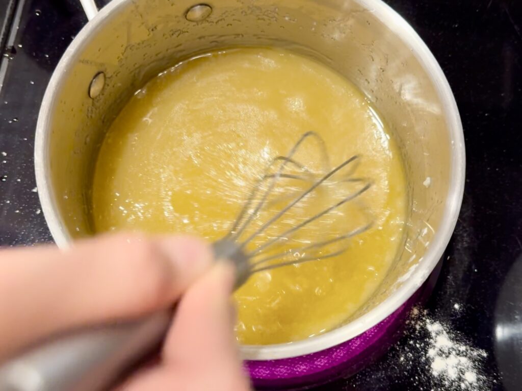 A girl whisking butter and sugar in a saucepan over the oven heat