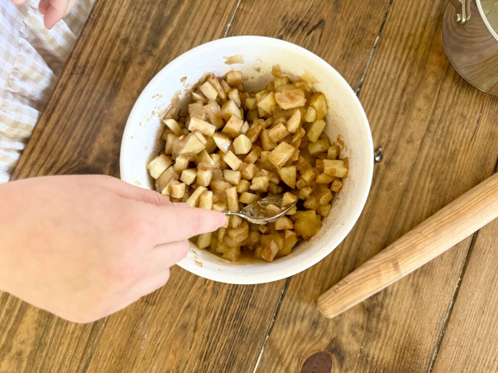 Girl mixing apple pie filling of diced apples, cinnamon and butter with sugar