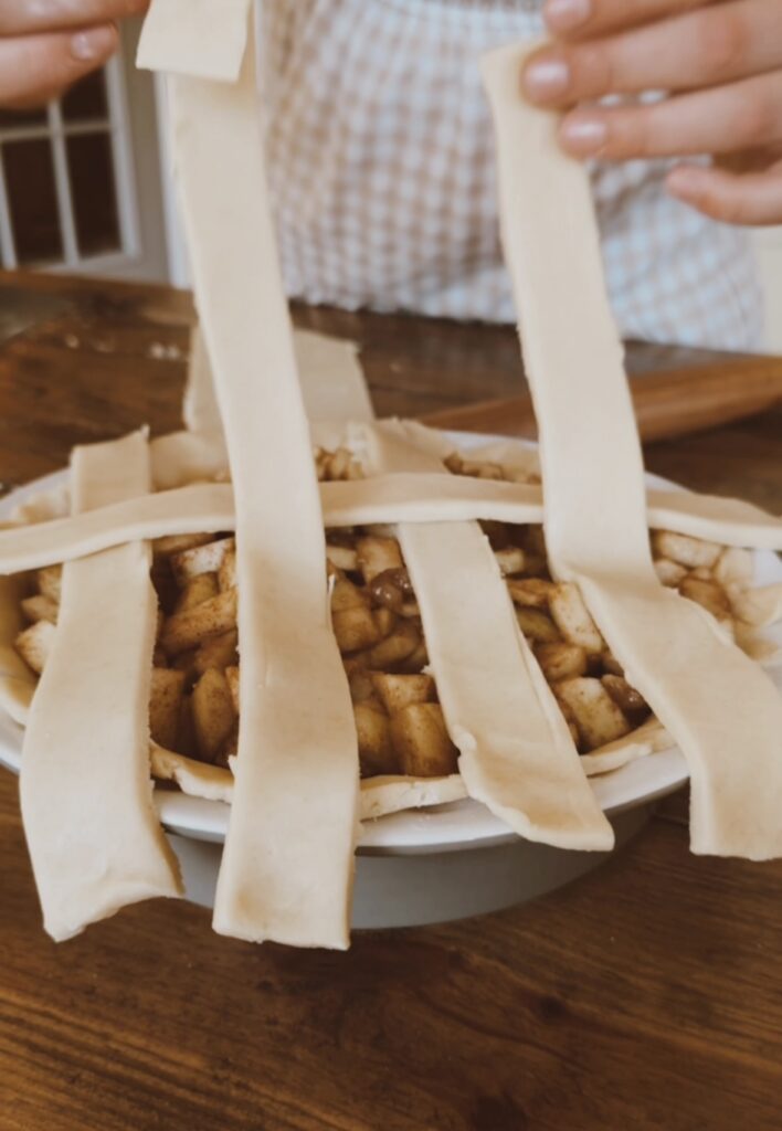 A girl demonstrating how to braid an apple pie top