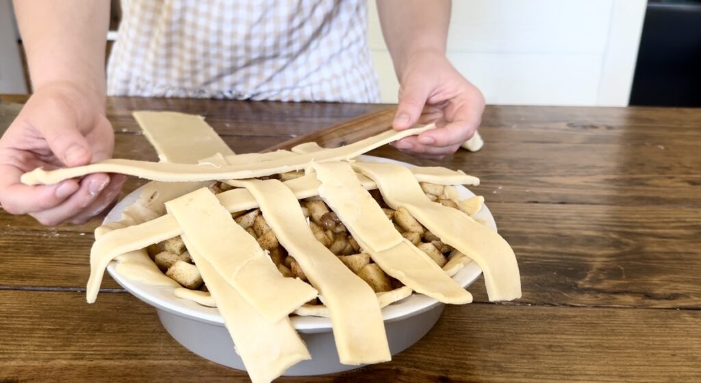 A girl demonstrating how to braid an apple pie top