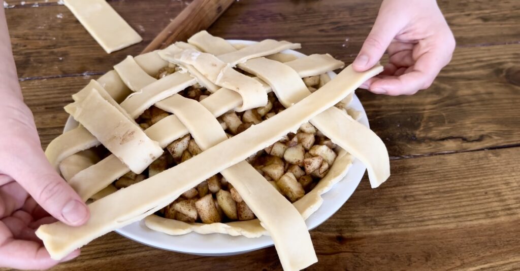 Girl using dough to braid an apple pie