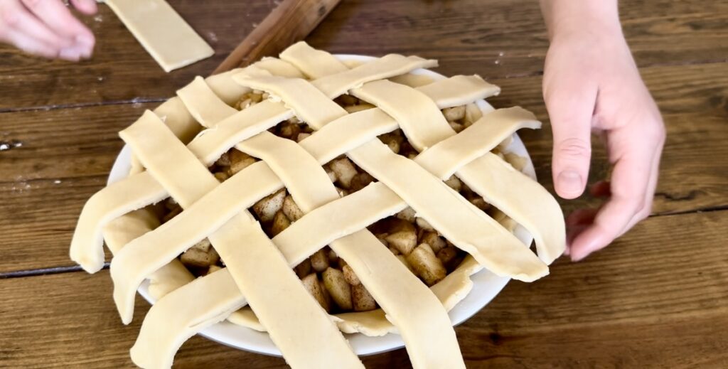 A girl demonstrating how to braid an apple pie top