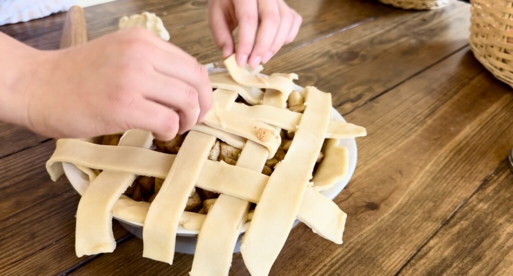 A girl demonstrating how to braid an apple pie top