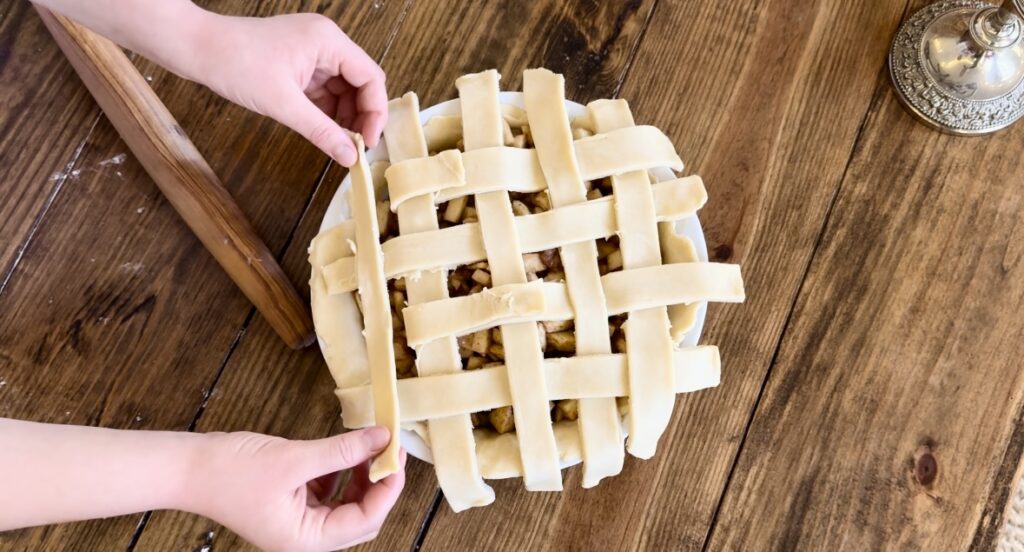 A girl demonstrating how to braid an apple pie top