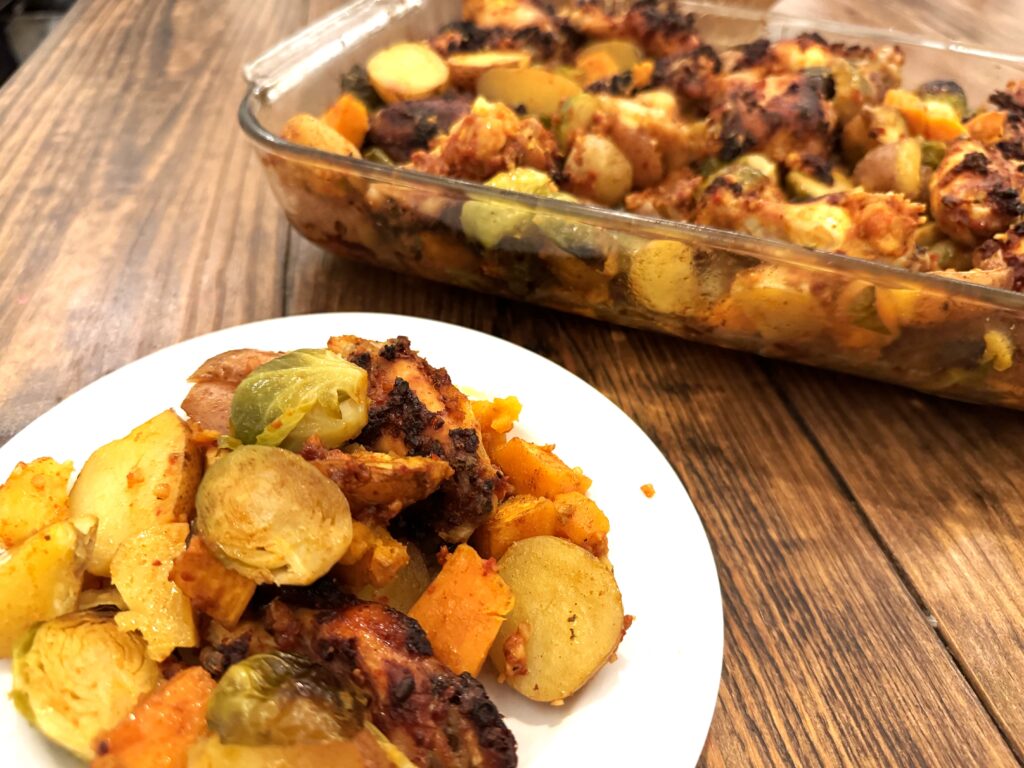 One glass pan and a plate of food with chicken and veggies