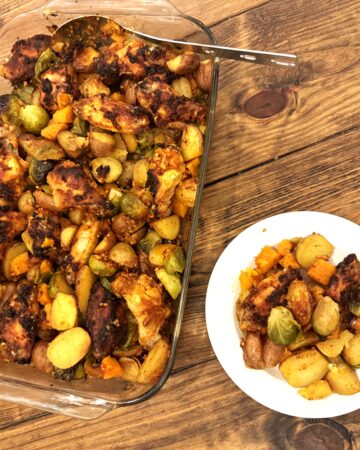 A table holding a glass pan and a dish with chicken and veggies