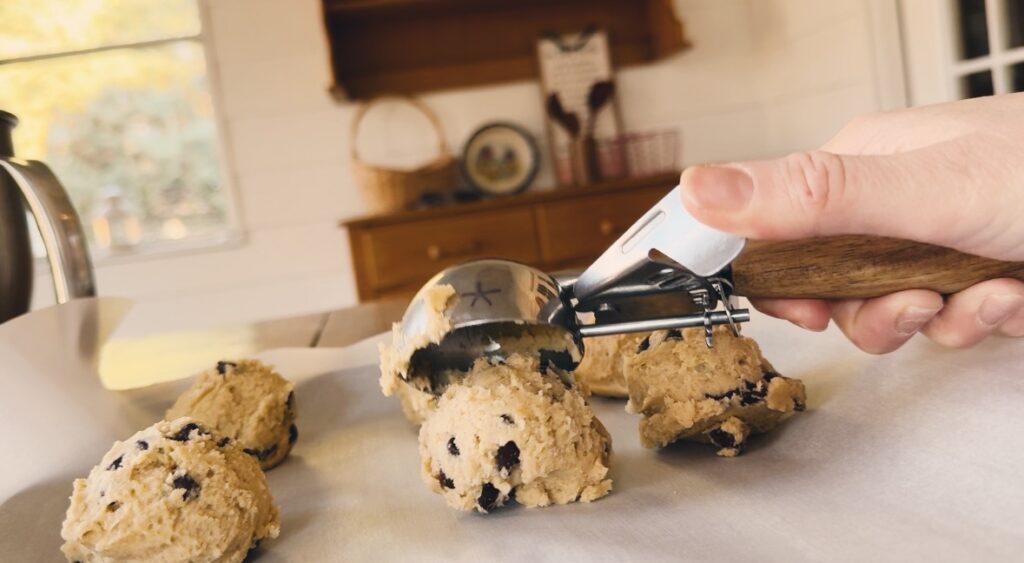 A girl placing cookie batter onto parchment paper.