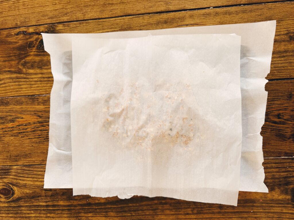 A wood table holding a mixture of ingredients covered with parchment paper.