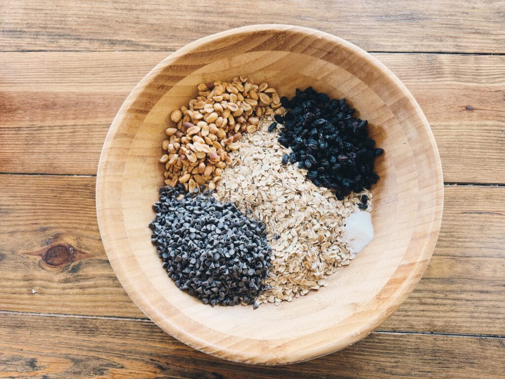 A wood table holding a wooden bowl filled with dry ingredients.