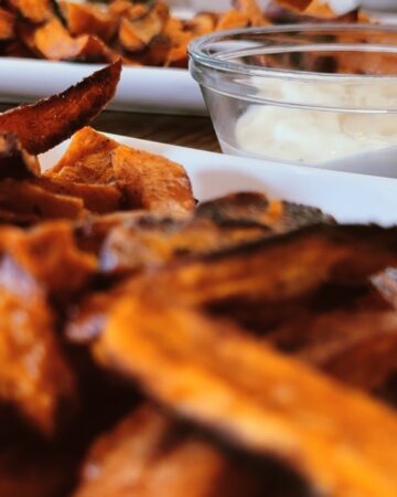 A close up of baked sweet potato fries on a white dish.