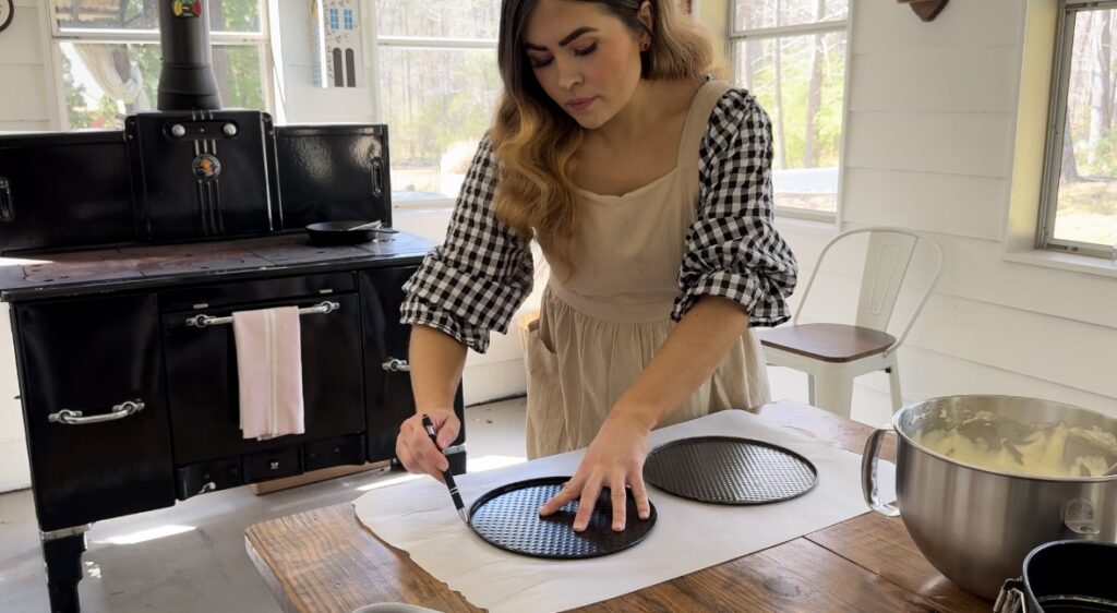 A girl cutting circles in parchment paper with cake pan rounds.