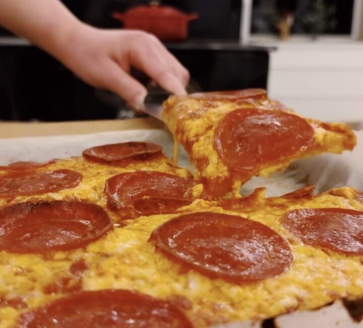 A girl holding a silced sourdough pepperoni pizza.